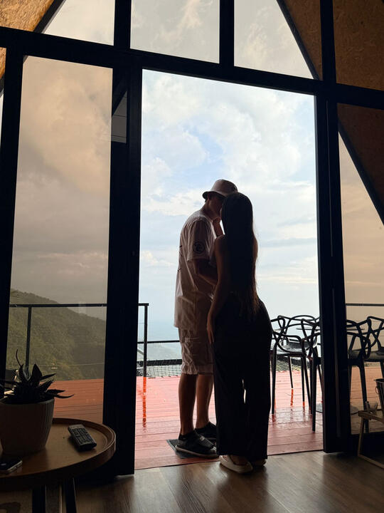 Pareja frente al ventanal de la cabaña con vista al valle